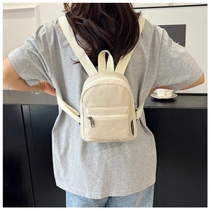 Dettaglio mini zaino in nylon crema con spallacci regolabili ed etichetta laterale