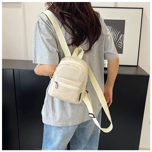 Dettaglio dello zaino mini in nylon crema con tasca anteriore e spallacci regolabili