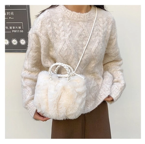 Detail of white faux fur plush bag featuring woven ring handles and soft pleated texture