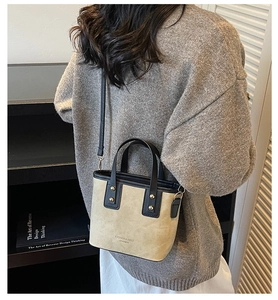 Detalle del mini bolso de ante beige con ribete de cuero negro y remaches dorados