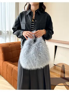 Détail d'un sac à main gris en fausse fourrure porté avec veste en cuir et jupe plissée