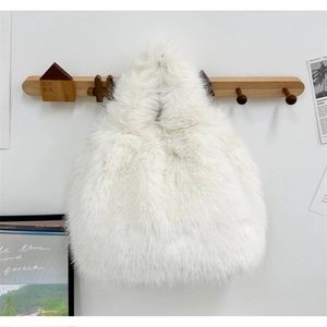 Détail d'un sac à main en fausse fourrure blanche suspendu à un crochet en bois mural