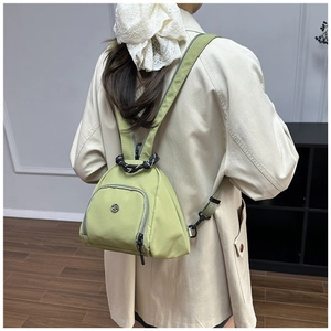 Detalle de la mochila triangular de nailon verde aguacate con asa trenzada en modelo