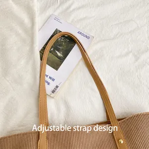 Detail of adjustable leather shoulder strap with rivets on brown corduroy tote bag