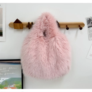 Détail de la texture d'un sac à main en fausse fourrure rose suspendu au crochet