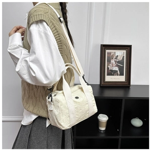 Detailed shot of an off-white casual canvas crossbody bag with wide shoulder strap and handles