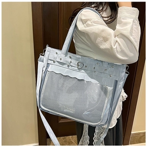 Model wearing light blue Ita bag with large transparent window and heart-shaped metal buckle