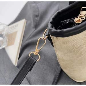 Détail du sac en toile kaki montrant la bordure en similicuir noir et ferrures dorées