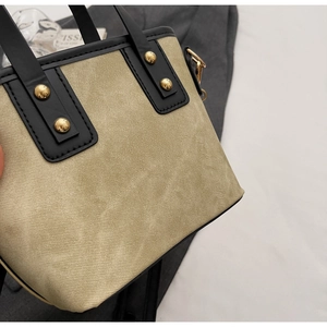 Détails de toile kaki et cuir noir avec rivets dorés sur le sac à main de luxe