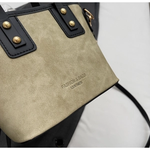 Détail du sac à main en cuir texturé vert olive avec bordure noire et clous dorés