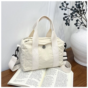 Close-up of off-white nylon handbag with metal logo on aesthetic magazine background