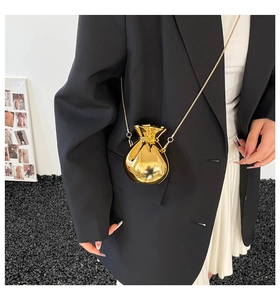 Dettaglio di una mini borsa a sacchetto dorata a specchio con tracolla a catena