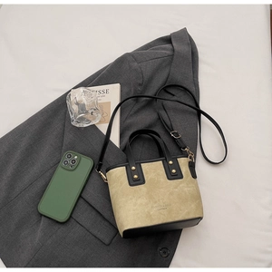 Détail du sac seau contrasté avec texture suédée, clous dorés et bandoulière