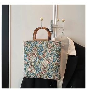Bolso tote floral con asas de bambú colgado en un vestidor con ropa