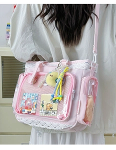 Detailansicht der rosa Ita-Bag mit Spitzenbesatz, Klarsichtfenster und Anhängern