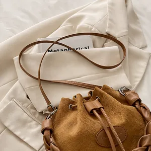 Close-up of a vintage brown suede bucket bag featuring woven handle and drawstring detail