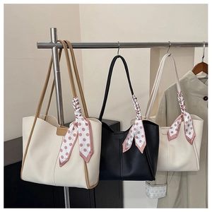 Detailed display of tote bags with silk scarves hanging on metal racks in shop scene