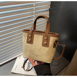 Gros plan détaillé du sac cabas en daim beige et cuir marron avec rivets métalliques