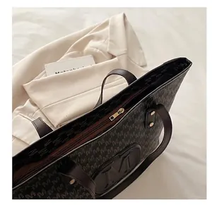 Close-up of smooth metal zipper and monogram print on the large brown tote bag