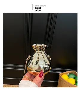 Dettaglio mini borsa da sera color oro chiaro a forma di caramella con catenina