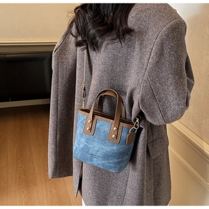 Détail du mini cabas en daim bleu avec garniture en cuir marron et rivets dorés élégants