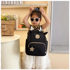 Dettaglio di un grazioso zaino nero per bambini con orecchie e stella indossato da bambina