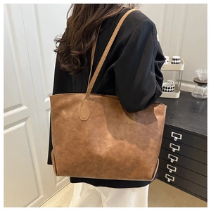 Side view of a large brown vintage tote bag worn by a model in a bright room