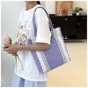 Detalle de un bolso tote de lona morada con encaje blanco decorativo y correa de hombro