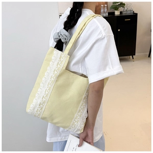Primer plano de bolso tote de lona amarilla con encaje blanco en hombro de modelo