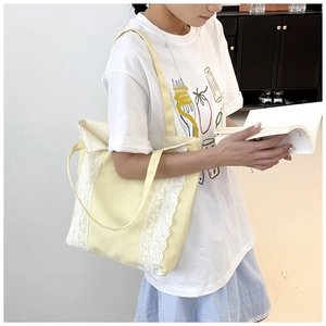 Detalle del bolso tote de lona amarilla con encaje blanco y correas para el hombro