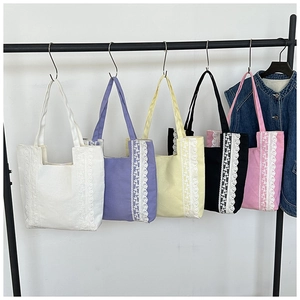 Detalle de cinco bolsos tote de lona coloridos con ribete de encaje vertical y bandolera