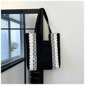 Detalle de las costuras de encaje floral blanco en el bolso tote de lona negra