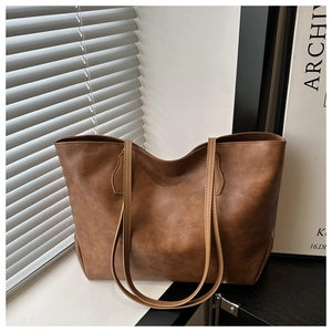 Macro shot of brown vintage tote bag showing fine leather texture and slim straps
