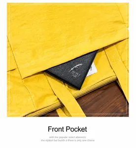 Detail of a bright yellow canvas tote bag showing the front pocket with a black diary inside