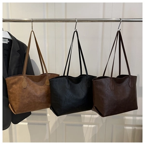 Three large leather tote bags in brown and black displayed on a minimalist rack