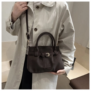 Close-up of deep brown suede tote bag with gold buckle and adjustable shoulder strap