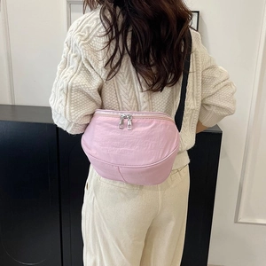 Sac banane rose en nylon avec zips argentés porté en bandoulière pour un style décontracté