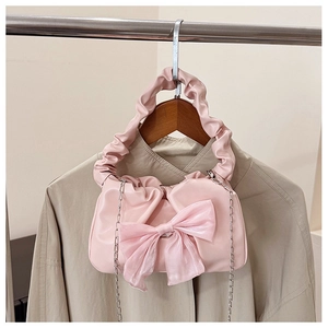 Dettaglio della borsa a mano plissettata rosa con grande fiocco e tracolla a catena