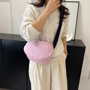 Détail du sac bandoulière rose clair en nylon avec sangle noire réglable et double fermeture