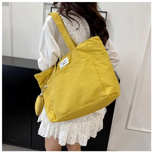 Detail of yellow nylon tote bag with textured fabric and hanging mini round coin purse