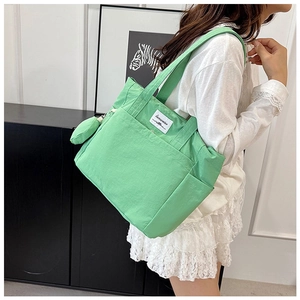 Detail view of a bright green canvas tote bag with front pocket and mini zipper pouch