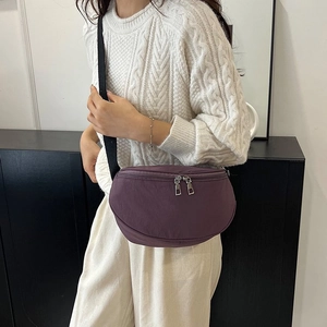 Détail d'un sac demi-lune en nylon violet foncé avec double fermeture éclair en métal