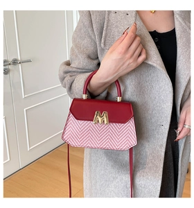 Détail du sac à main tissé rouge et blanc avec boucle dorée et rabat en cuir de qualité