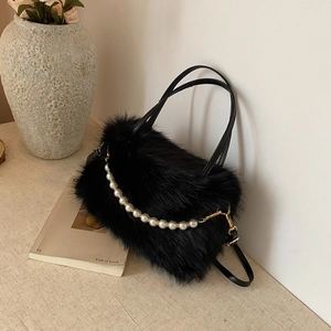 Dettaglio borsa in ecopelliccia nera con catena di perle eleganti e manici sottili chic