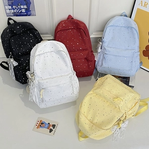 Détail de sacs à dos à motif d'étoiles en cinq couleurs avec breloques noeud en dentelle