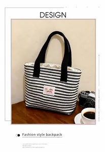 Nahaufnahme der schwarz-weiß gestreiften Canvas-Tasche mit rosa Logo auf Holztisch