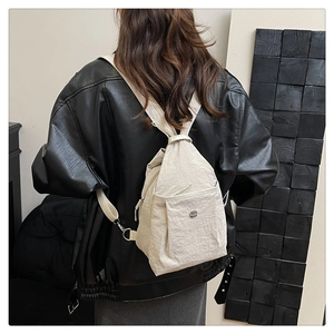 Detail of beige nylon drawstring backpack with metal logo shown on model back