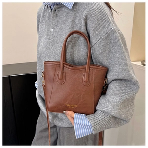 Detail of dark caramel faux leather tote with gold logo and cylindrical handles