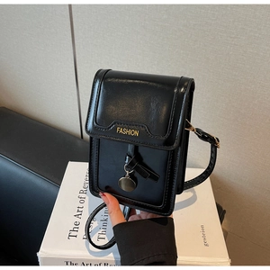 Close-up of black glossy mini phone bag with golden fashion letter and metal charm