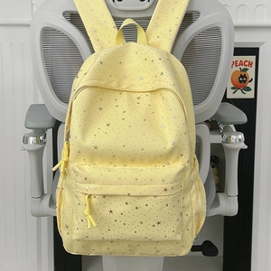 Détail du sac à dos jaune clair avec motif étoiles argentées et poches zippées